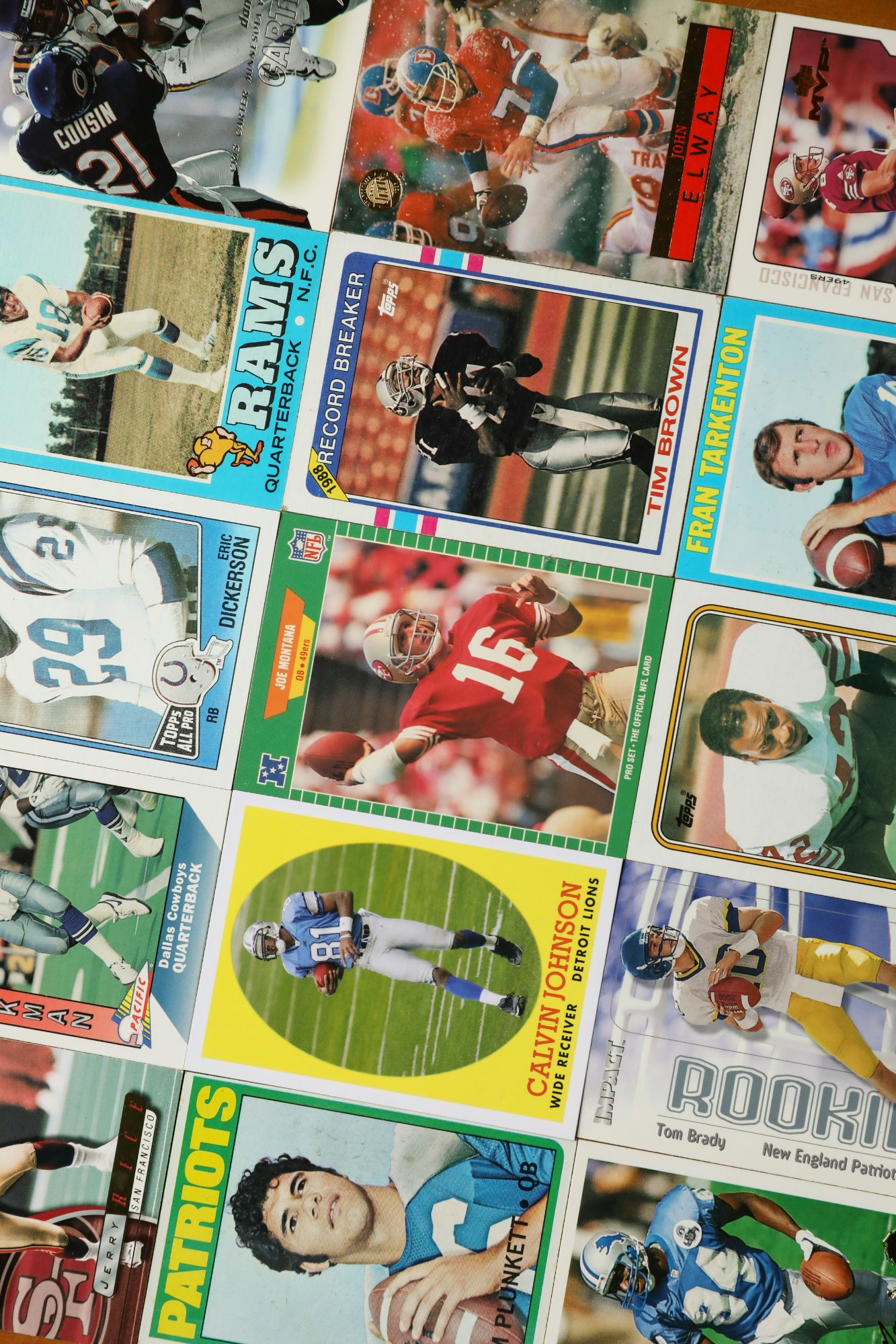 Vintage sports cards spread out on a table — football cards including Joe Montana, Tim Brown, John Elway and others